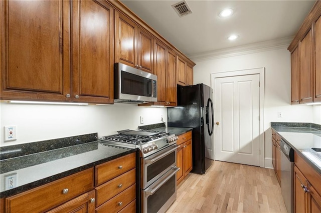 kitchen featuring dark stone countertops, ornamental molding, light hardwood / wood-style floors, and appliances with stainless steel finishes