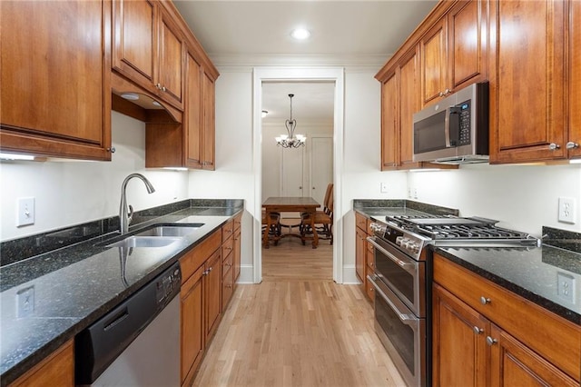 kitchen featuring an inviting chandelier, stainless steel appliances, sink, and dark stone counters