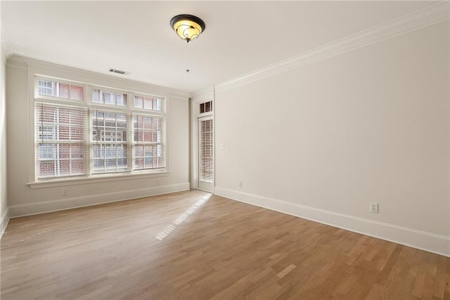 unfurnished room with ornamental molding and light wood-type flooring