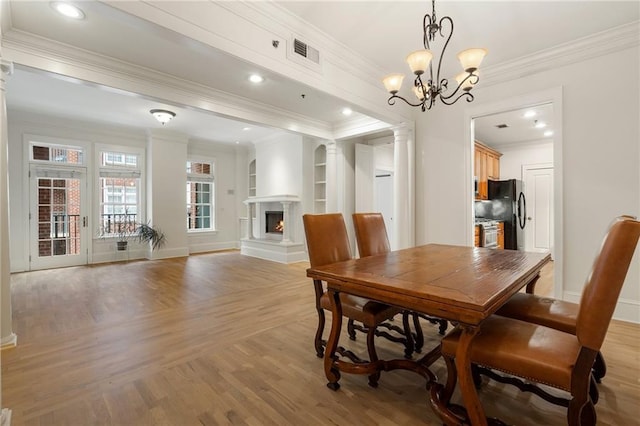 dining room with built in features, ornamental molding, light hardwood / wood-style flooring, and ornate columns