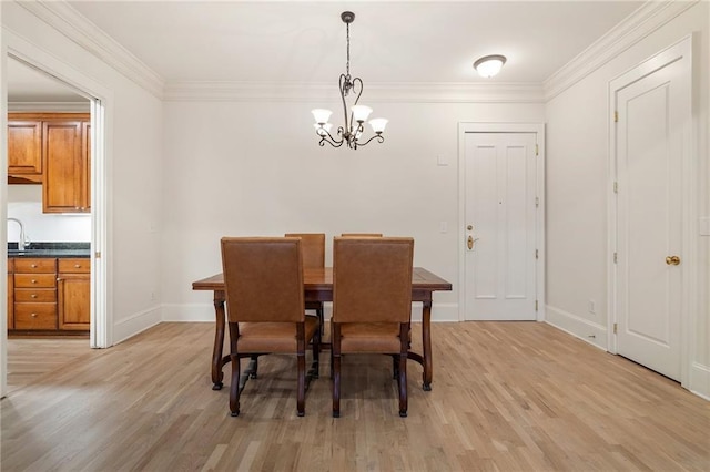 dining space featuring ornamental molding, sink, a chandelier, and light wood-type flooring