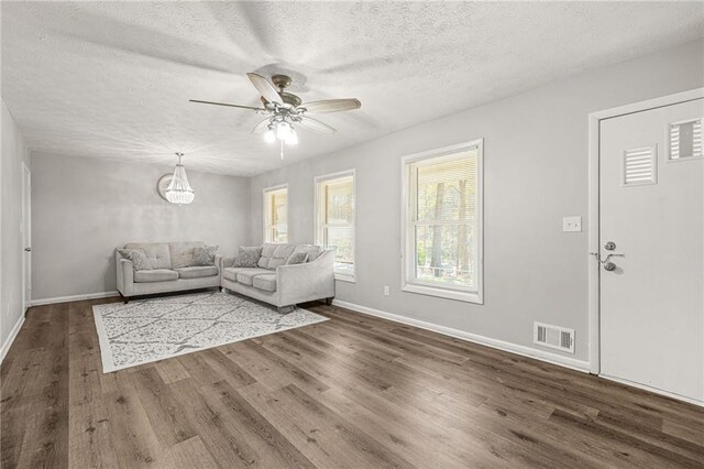 4218 Hideaway Dr, Tucker, GA 30084 - unfurnished living room with dark wood-style flooring, a textured ceiling, visible vents, baseboards, and ceiling fan with notable chandelier