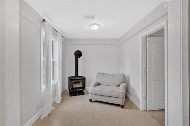 living area with light tile patterned flooring and a wood stove