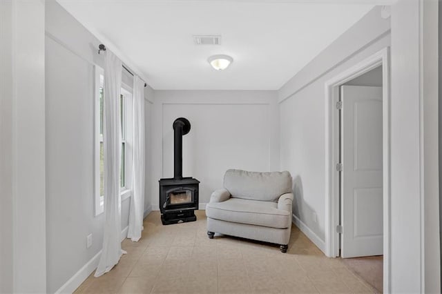 living area with a wood stove and light tile patterned floors