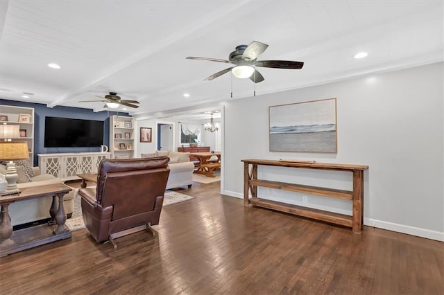 living room with ceiling fan with notable chandelier, built in shelves, dark hardwood / wood-style flooring, and beam ceiling