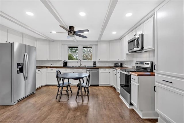 kitchen with white cabinets, stainless steel appliances, hardwood / wood-style floors, and sink