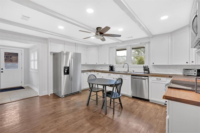 kitchen featuring white cabinetry, stainless steel appliances, sink, wood-type flooring, and wooden counters