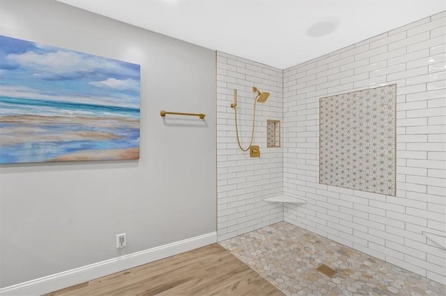 bathroom with hardwood / wood-style floors and tiled shower