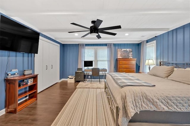 bedroom featuring dark wood-type flooring, a closet, ceiling fan, and beam ceiling