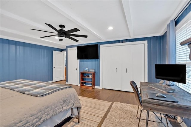 bedroom featuring beam ceiling, ceiling fan, dark hardwood / wood-style flooring, and two closets