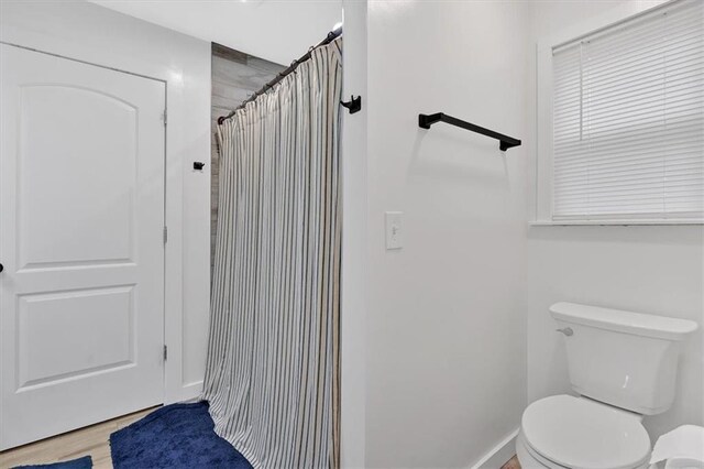 bathroom with hardwood / wood-style flooring, curtained shower, and toilet