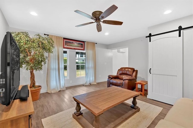 living room with ceiling fan, light hardwood / wood-style floors, and a barn door