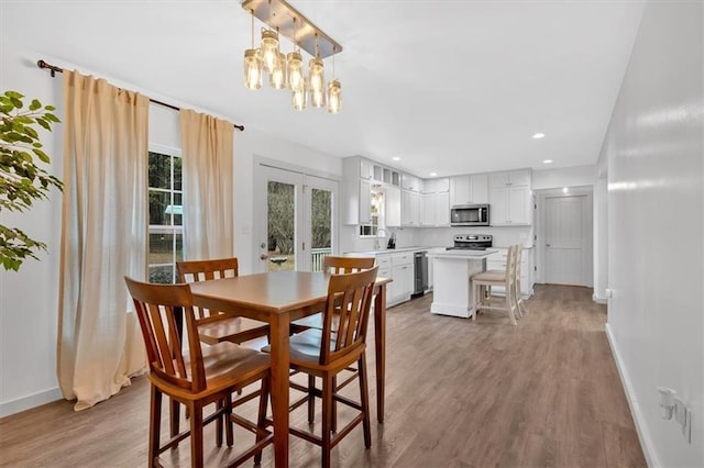 dining space featuring sink, french doors, and wood-type flooring