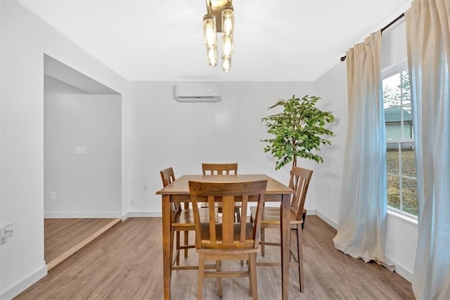 dining room with a notable chandelier, a wall mounted air conditioner, plenty of natural light, and light hardwood / wood-style flooring