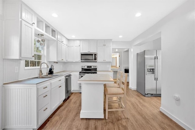 kitchen with white cabinetry, a center island, a breakfast bar, sink, and appliances with stainless steel finishes