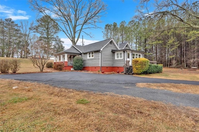 view of side of home featuring covered porch and a yard