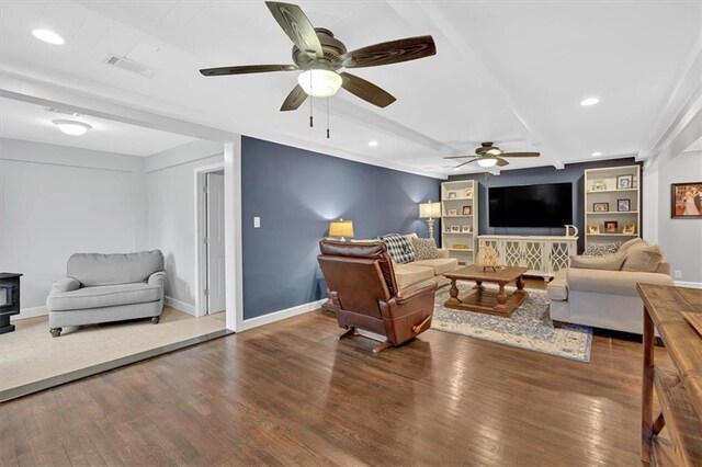 living room featuring a wood stove, hardwood / wood-style flooring, ceiling fan, and built in features