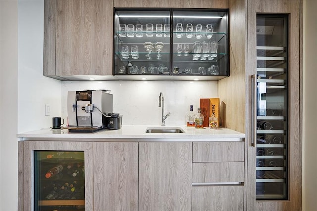 bar with sink, light brown cabinets, and beverage cooler