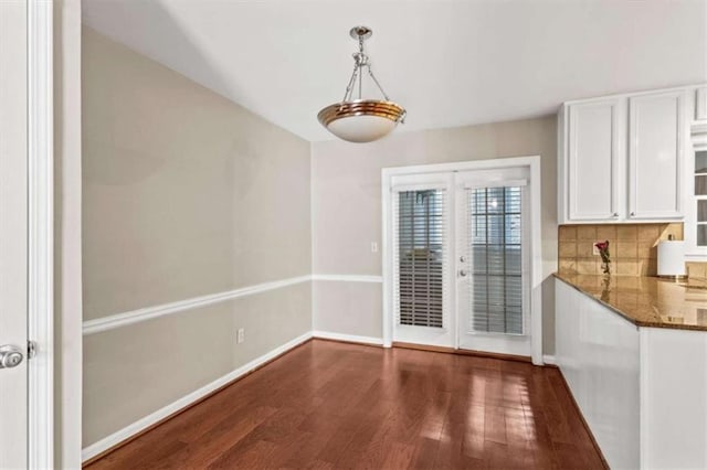 unfurnished dining area with wood finished floors and baseboards