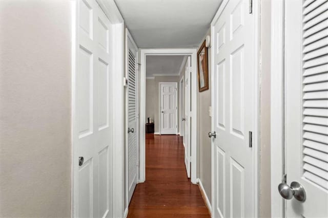hallway with dark wood-type flooring and baseboards