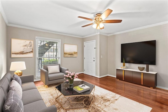 living room featuring wood finished floors, crown molding, ceiling fan, and baseboards