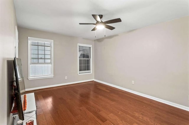 unfurnished room featuring baseboards, wood finished floors, and ceiling fan