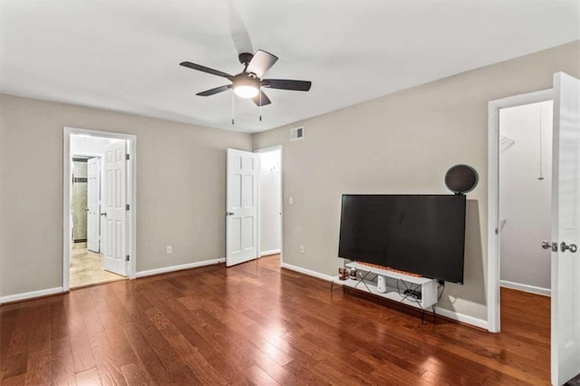 unfurnished living room with ceiling fan, hardwood / wood-style flooring, and baseboards