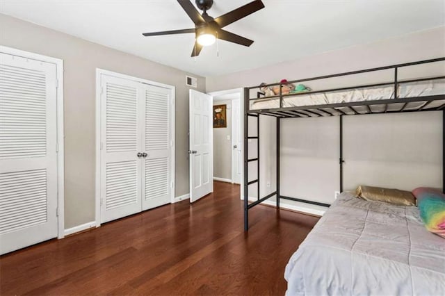 bedroom featuring wood finished floors, multiple closets, baseboards, and ceiling fan