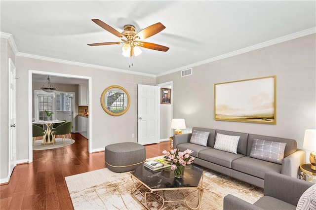 living area featuring a ceiling fan, wood finished floors, crown molding, and baseboards