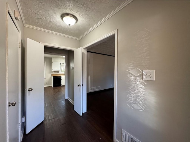 corridor featuring a textured ceiling, dark hardwood / wood-style flooring, and crown molding