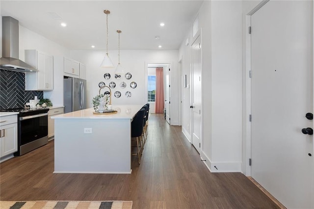 989 Bibbs Cir NW Unit 25, Atlanta, GA 30318 - kitchen with stainless steel appliances, wall chimney exhaust hood, light countertops, dark wood-type flooring, and backsplash