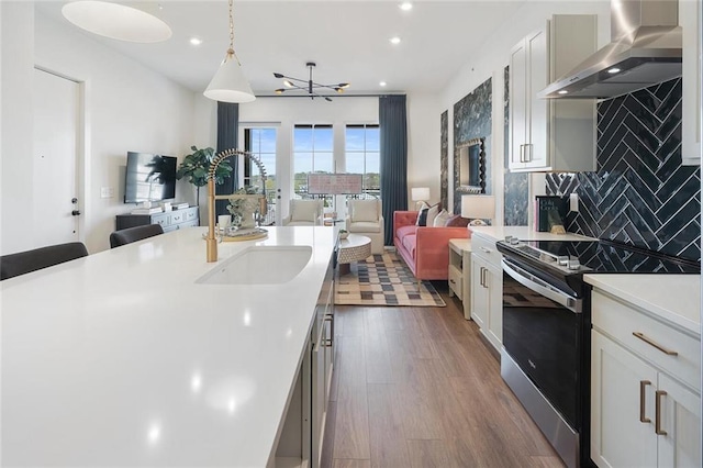 989 Bibbs Cir NW Unit 25, Atlanta, GA 30318 - kitchen with wall chimney range hood, stainless steel electric range, open floor plan, light countertops, and decorative backsplash