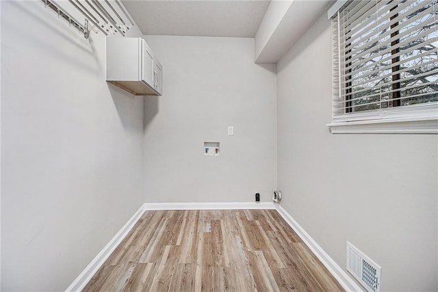 washroom featuring visible vents, light wood-style flooring, cabinet space, and washer hookup