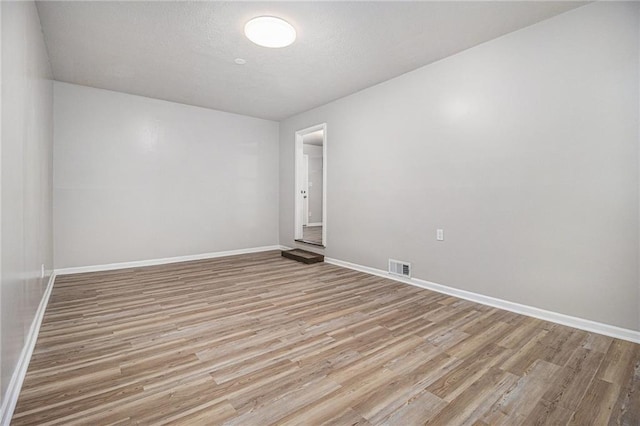 spare room featuring baseboards, light wood finished floors, and visible vents