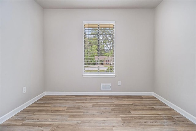 empty room with baseboards, visible vents, and wood finished floors