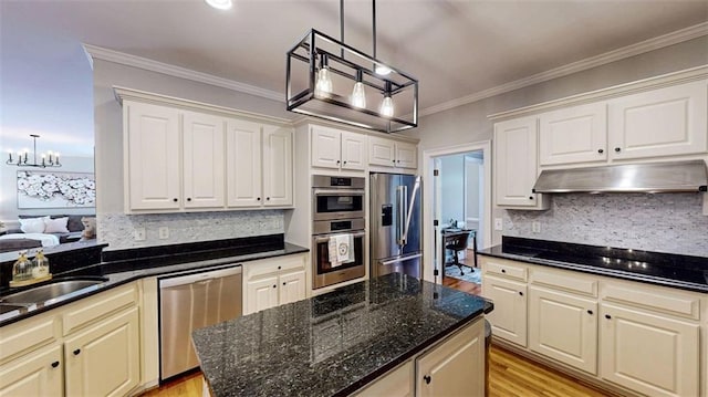 kitchen with appliances with stainless steel finishes, under cabinet range hood, a chandelier, backsplash, and pendant lighting