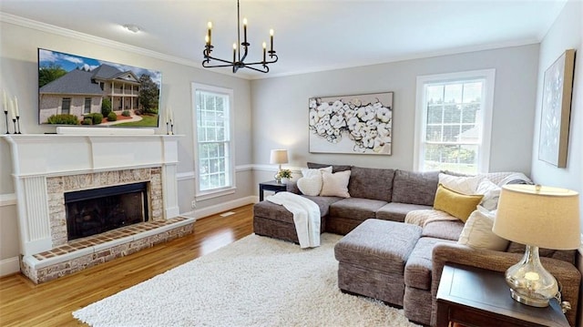 living area featuring a chandelier, wood finished floors, crown molding, baseboards, and a fireplace with raised hearth