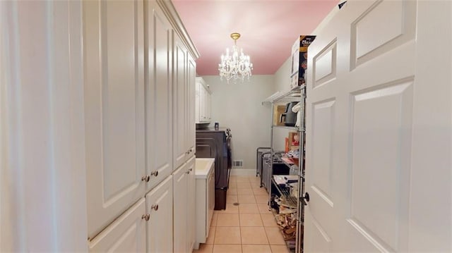 hallway featuring separate washer and dryer, a chandelier, and light tile patterned floors