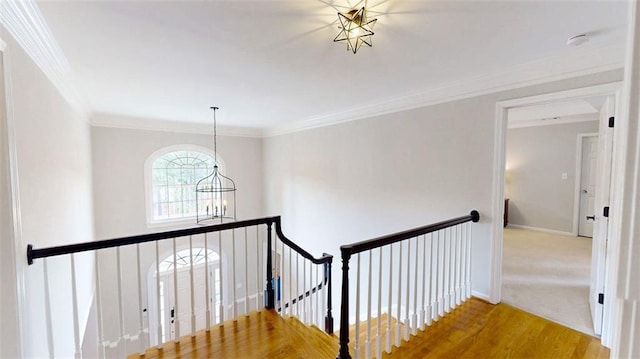 stairway featuring a chandelier, crown molding, baseboards, and wood finished floors