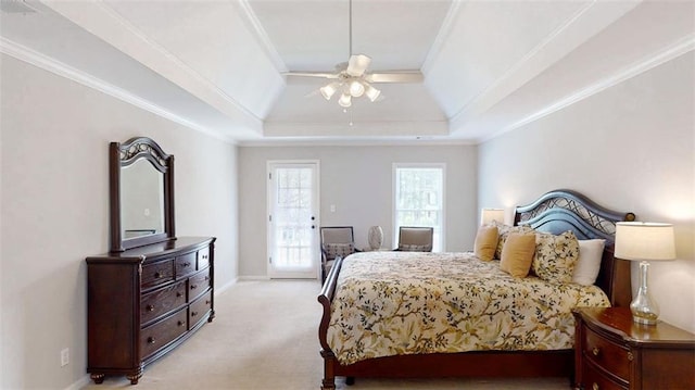 bedroom featuring light carpet, ornamental molding, a tray ceiling, and a ceiling fan
