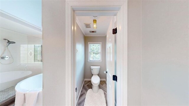 full bathroom featuring toilet, a shower, crown molding, and baseboards