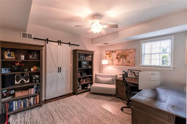 office with a barn door and a ceiling fan