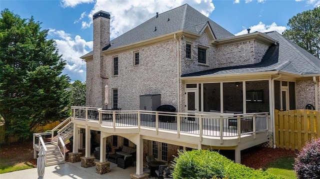back of house featuring a patio area, a wooden deck, a chimney, a sunroom, and stairway