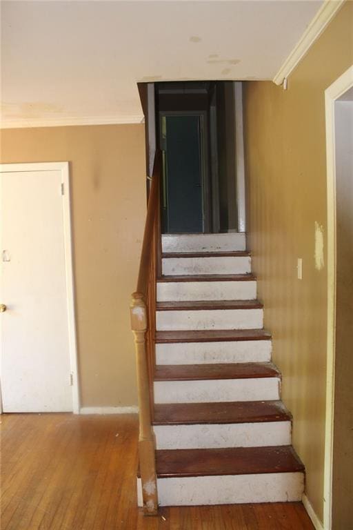 stairs with baseboards, ornamental molding, and wood finished floors