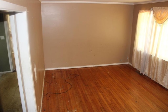 empty room featuring crown molding, baseboards, and wood finished floors