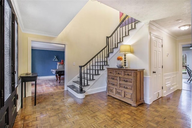 foyer entrance featuring crown molding, parquet flooring, and a textured ceiling