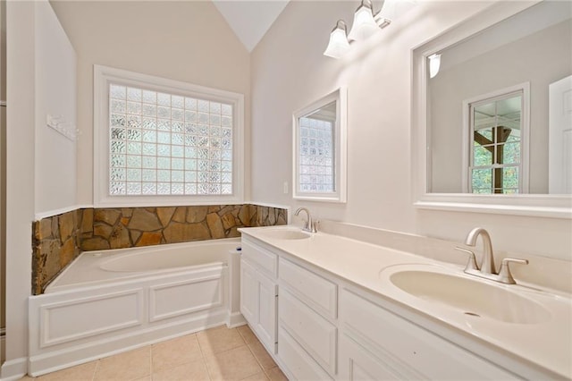 bathroom featuring tile patterned floors, lofted ceiling, a garden tub, and a sink