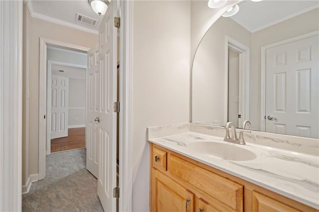 bathroom with visible vents, baseboards, vanity, and crown molding