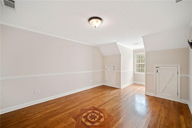 additional living space featuring wood finished floors, visible vents, and baseboards