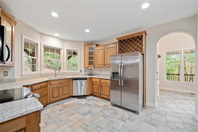 kitchen featuring baseboards, recessed lighting, a sink, stainless steel appliances, and stone finish floor